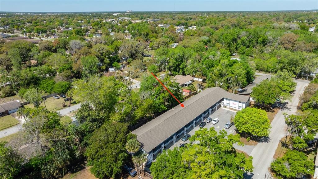 An aerial view shows a long, single-story apartment building with a parking lot and surrounding trees — 1216 KENNEDY ROAD, DAYTONA BEACH, FL
