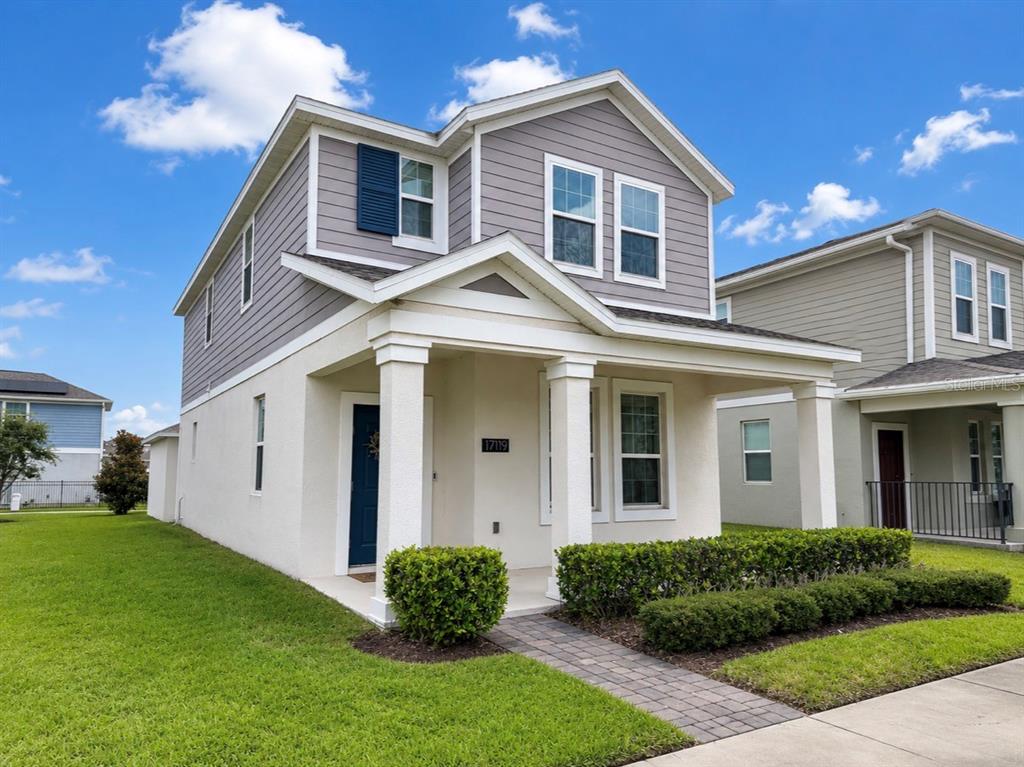 A two-story house with gray siding, a white stucco front, and a covered porch — 17119 QUICKSILVER AVENUE, WINTER GARDEN, FL