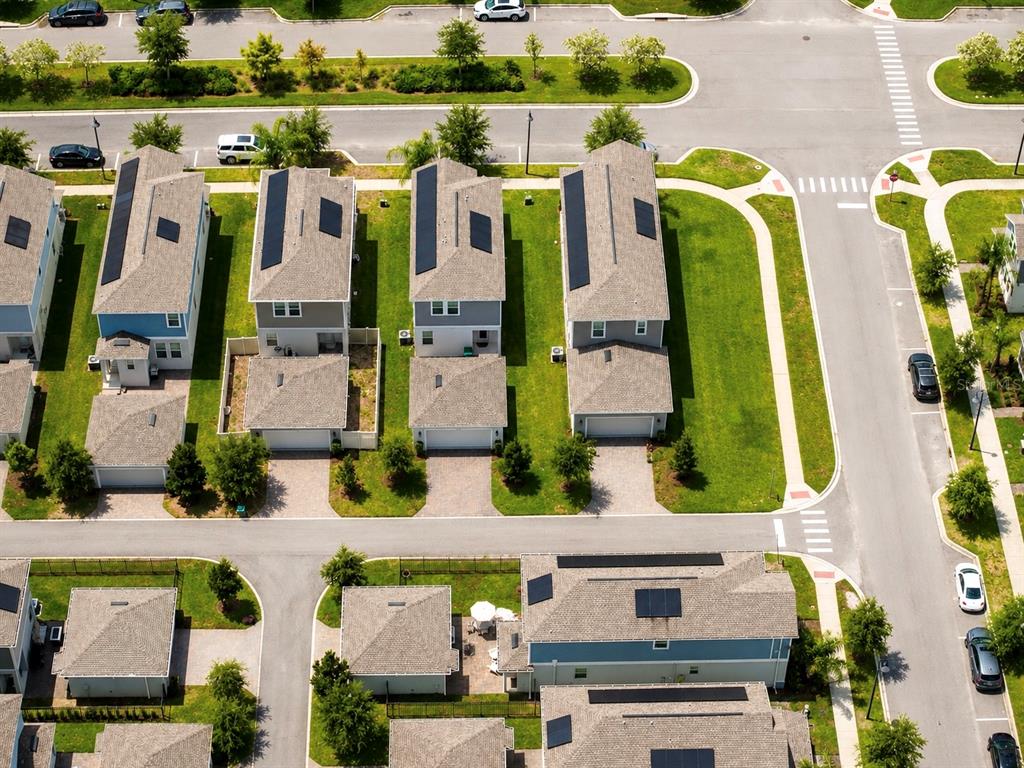 An aerial view shows several suburban houses with solar panels on their shingled roofs — 17119 QUICKSILVER AVENUE, WINTER GARDEN, FL