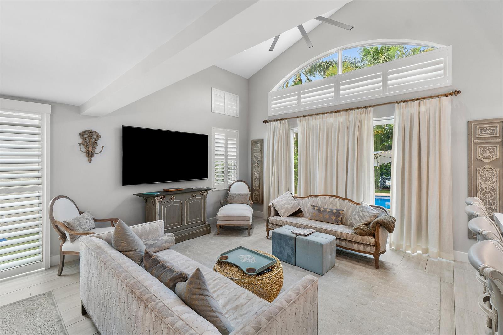 A living room features a vaulted ceiling, a large television, and a view of a pool — 2550 NW 52nd Street, Boca Raton FL 33496, BOCA RATON, FL