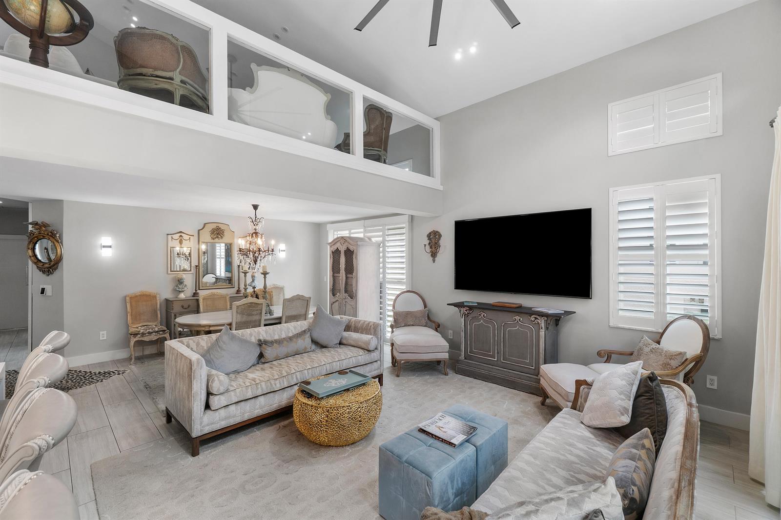 A living room with a lofted area, neutral furniture, a large television, and dining space — 2550 NW 52nd Street, Boca Raton FL 33496, BOCA RATON, FL