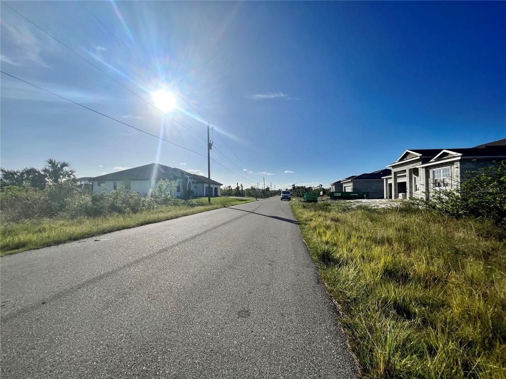 A paved road leads past a house under construction and a vacant lot — 15755 STAUNTON CIRCLE, PORT CHARLOTTE, FL