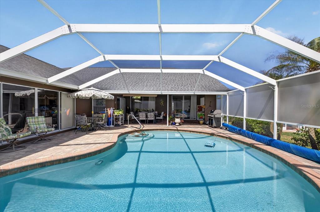 A screened-in patio features a swimming pool, brick pavers, and outdoor furniture — 8687 ASHBURY DRIVE, HUDSON, FL