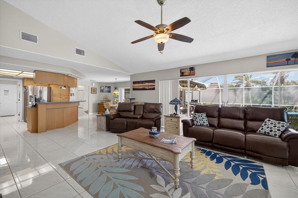 A living room with tile floors, brown leather furniture, and a ceiling fan — 8687 ASHBURY DRIVE, HUDSON, FL
