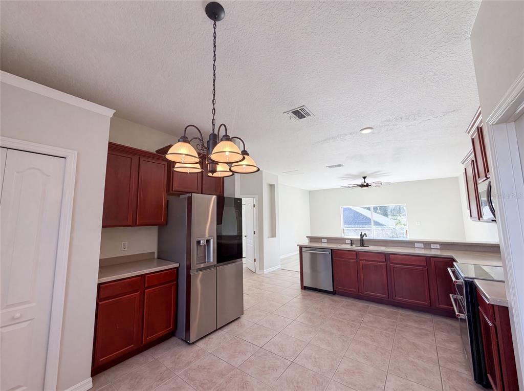 A kitchen with dark wood cabinets, stainless steel appliances, and tile flooring — 204 ROUND MAN STREET, LEESBURG, FL