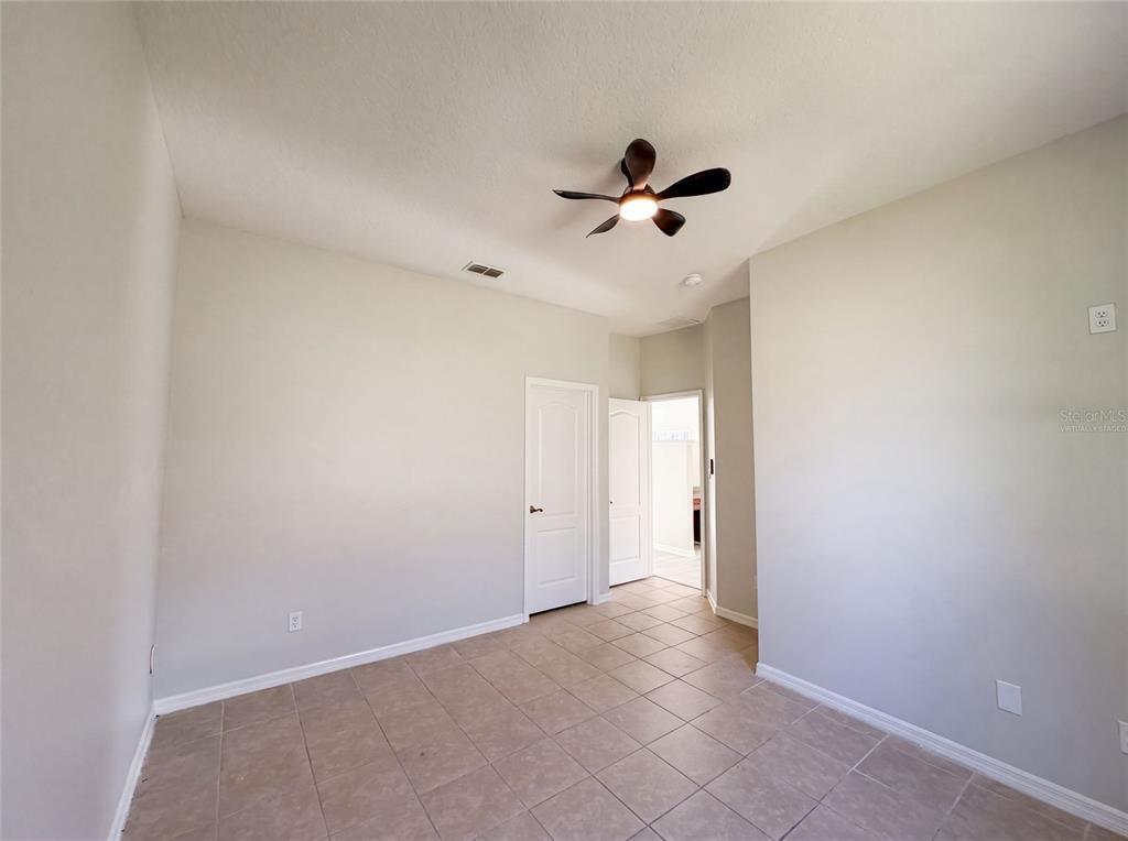 An empty room features light-colored walls, tile flooring, a ceiling fan, and two doorways — 204 ROUND MAN STREET, LEESBURG, FL