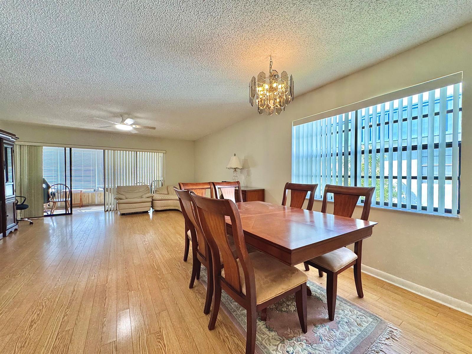 A dining room with a wooden table, chairs, chandelier, and light-colored wood flooring — 565 Piedmont L, Delray Beach FL 33484, DELRAY BEACH, FL