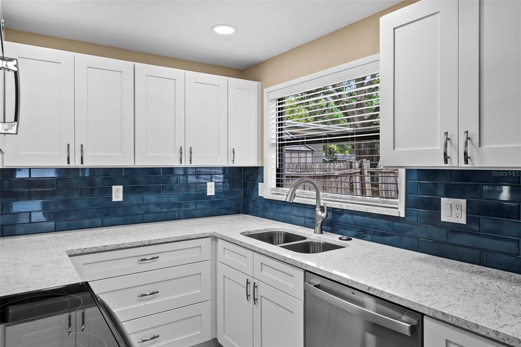 A kitchen features white cabinets, speckled countertops, and a blue subway tile backsplash — 1193 & 1195 BASS BOULEVARD, DUNEDIN, FL