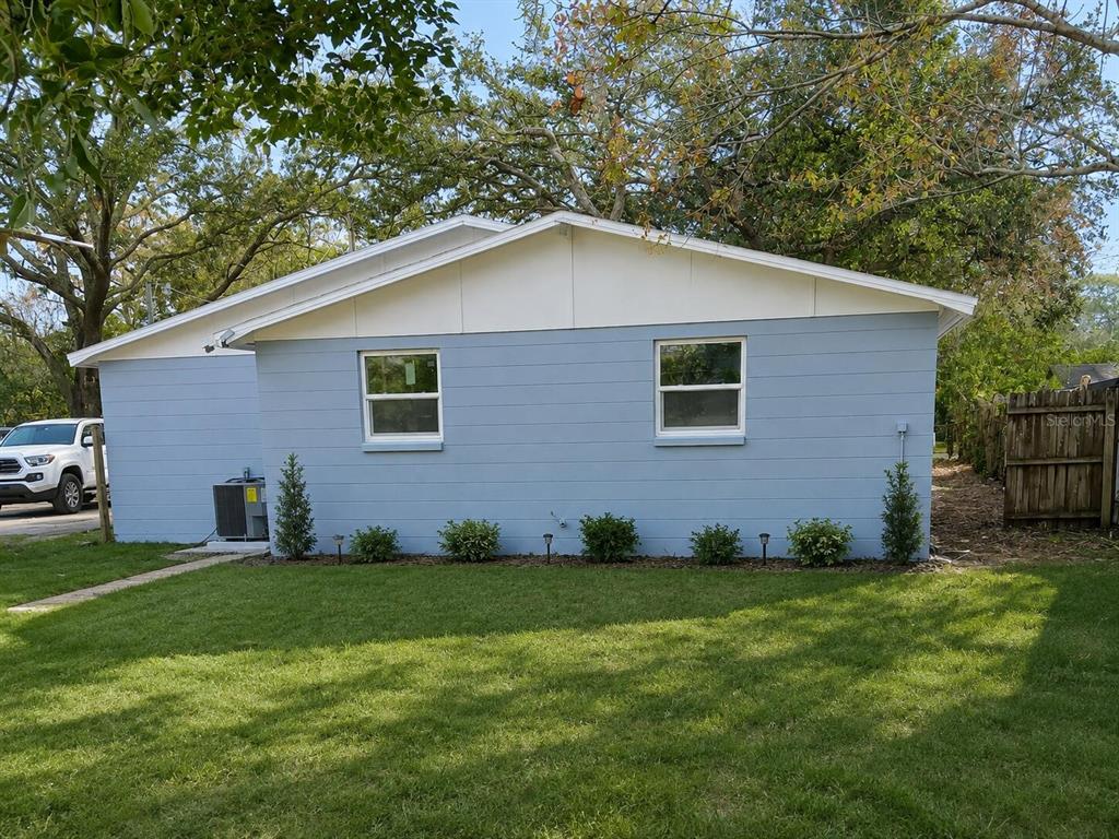 A light blue, single-story house with a white gable and two windows sits on grass — 7510 ALMARK STREET, TAMPA, FL