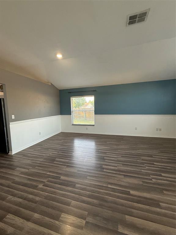 An empty room features wood-look flooring, white wainscoting, and blue and gray painted walls — 5841 DORHAM PLACE, WESLEY CHAPEL, FL
