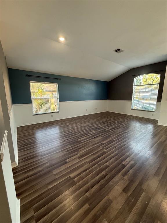 An empty room features wood-look flooring, white wainscoting, and two windows with blinds — 5841 DORHAM PLACE, WESLEY CHAPEL, FL