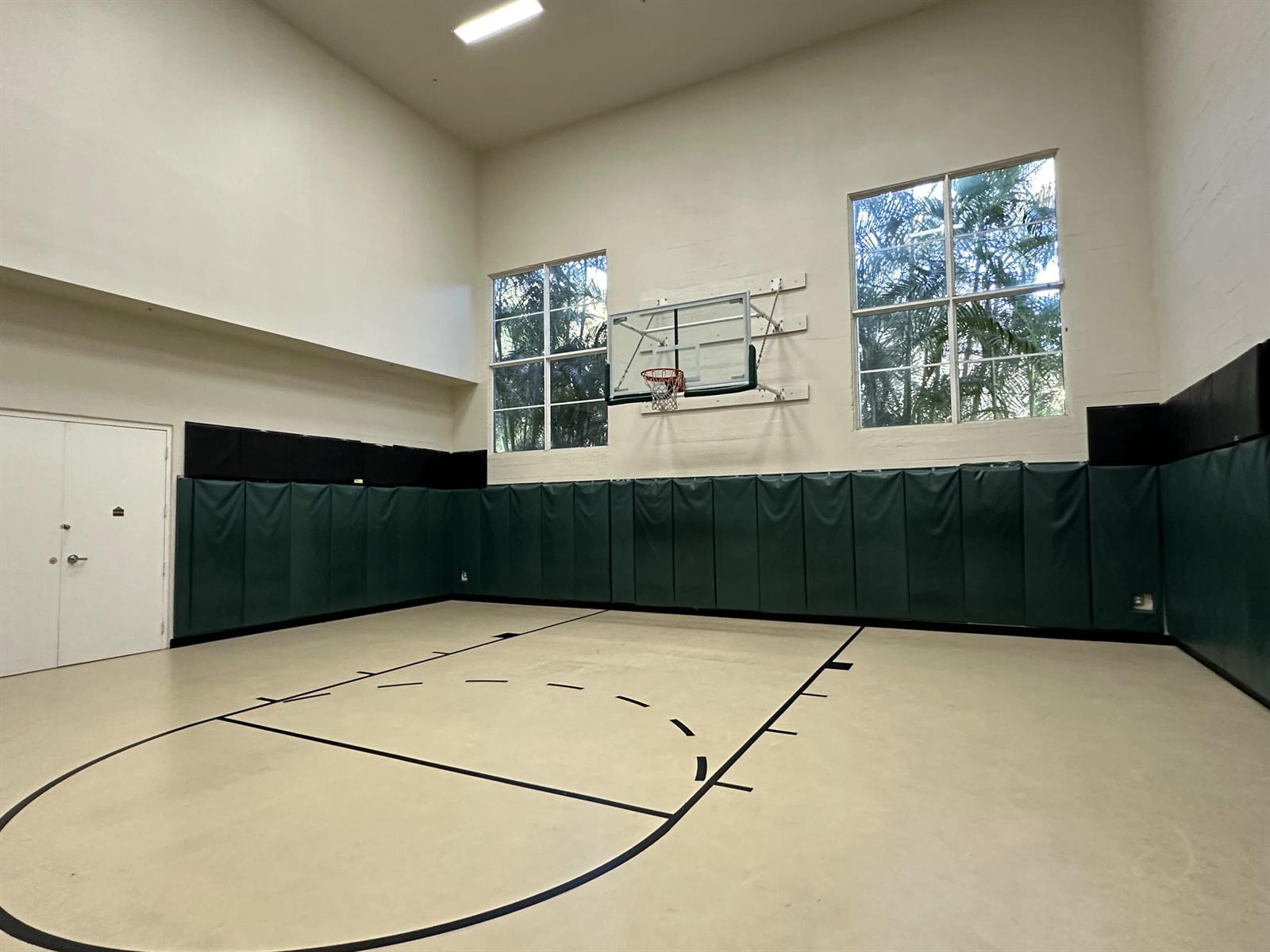 An indoor basketball court features a hoop, green wall padding, and large windows — 1660 Renaissance Commons Boulevard # 2507, Boynton Beach FL 33426, BOYNTON BEACH, FL