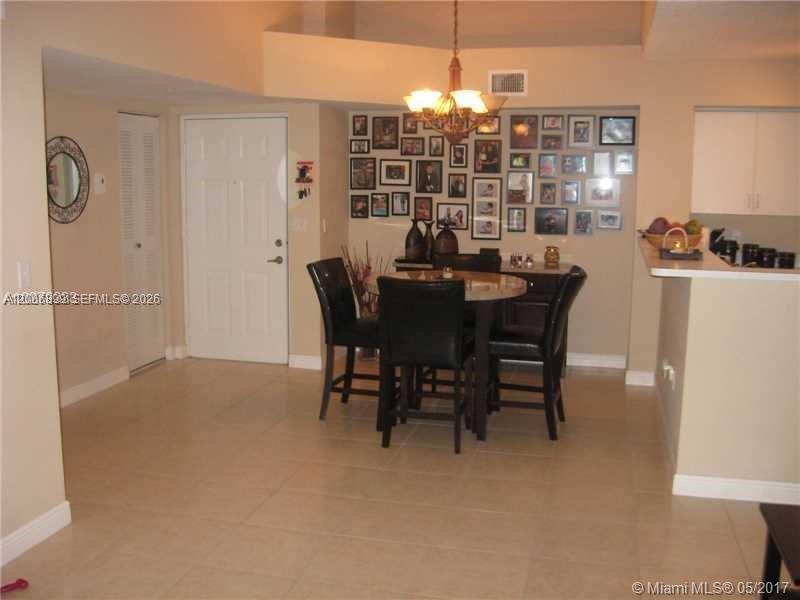 A dining area features a round table with four chairs and a wall of framed photos — 2071 Renaissance Blvd # 305, Miramar FL 33025, MIRAMAR, FL
