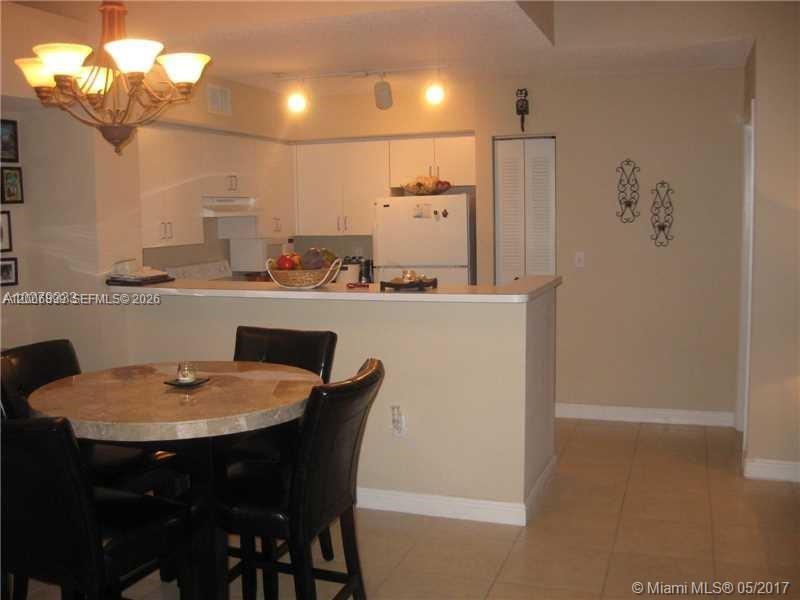 A dining area with a round table and chairs sits in front of a kitchen — 2071 Renaissance Blvd # 305, Miramar FL 33025, MIRAMAR, FL