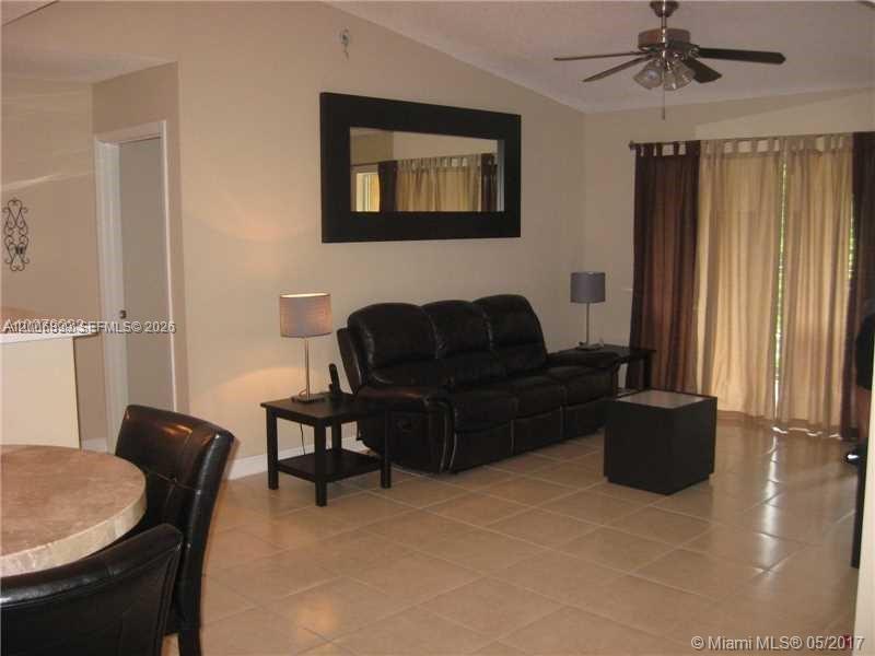 A living room features a black leather sofa, a mirror, and tile flooring — 2071 Renaissance Blvd # 305, Miramar FL 33025, MIRAMAR, FL