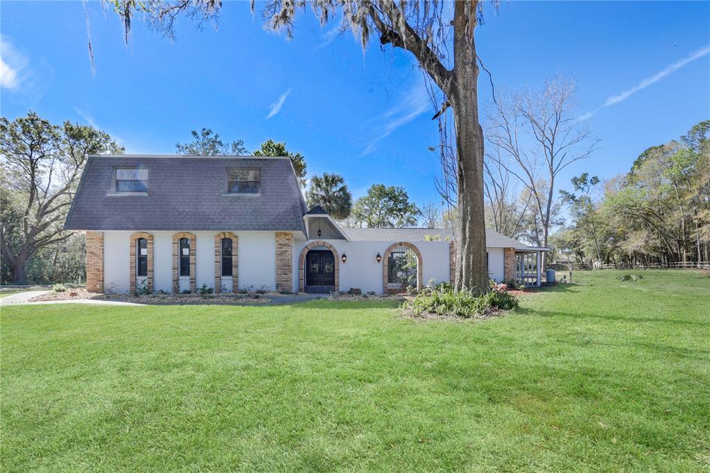 A two-story house with a mansard roof, arched windows, and a large tree in front — 2830 SE 31ST STREET, OCALA, FL