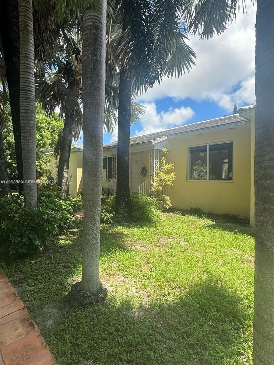 A yellow single-story house exterior features a front entrance, windows, and surrounding palm trees — 1015 NE 112th St, Biscayne Park FL 33161, BISCAYNE PARK, FL