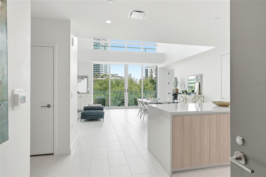 A bright, open-concept living and dining area features white tile floors and floor-to-ceiling windows — 400 CENTRAL AVENUE UNIT 303, ST PETERSBURG, FL