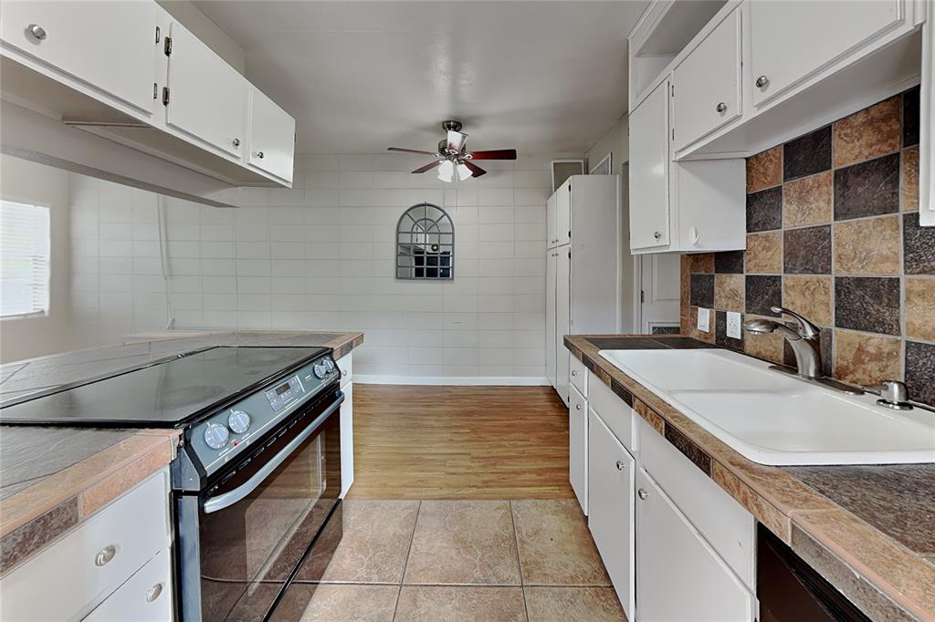 A kitchen features white cabinets, tiled countertops, a double sink, and a dining area beyond — 313 S LAWSONA BOULEVARD, ORLANDO, FL