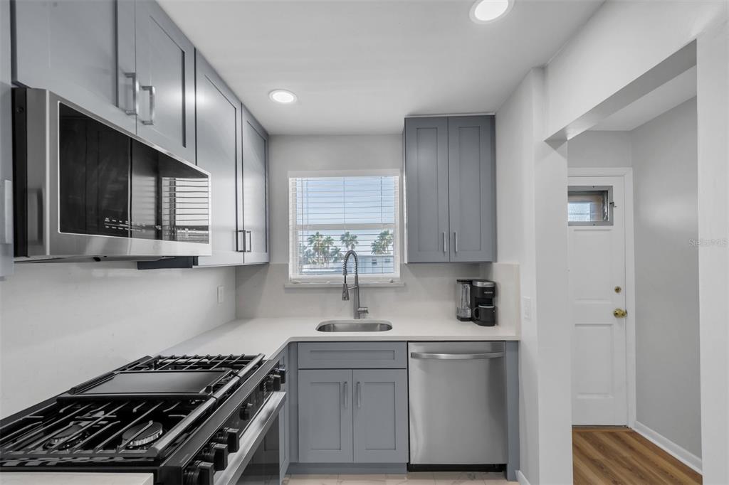 A kitchen features gray cabinets, stainless steel appliances, a gas range, and a white countertop — 3128 59TH STREET S UNIT 303, GULFPORT, FL