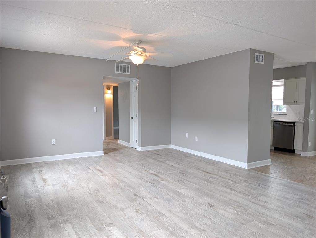 A living room with light gray walls, wood-look flooring, and a ceiling fan — 6990 PLACE DE LA PAIX UNIT 1A, SOUTH PASADENA, FL