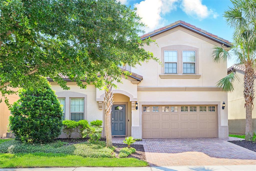 A two-story house with a beige stucco exterior, a two-car garage, and a paved driveway — 1893 GOBI DRIVE, KISSIMMEE, FL