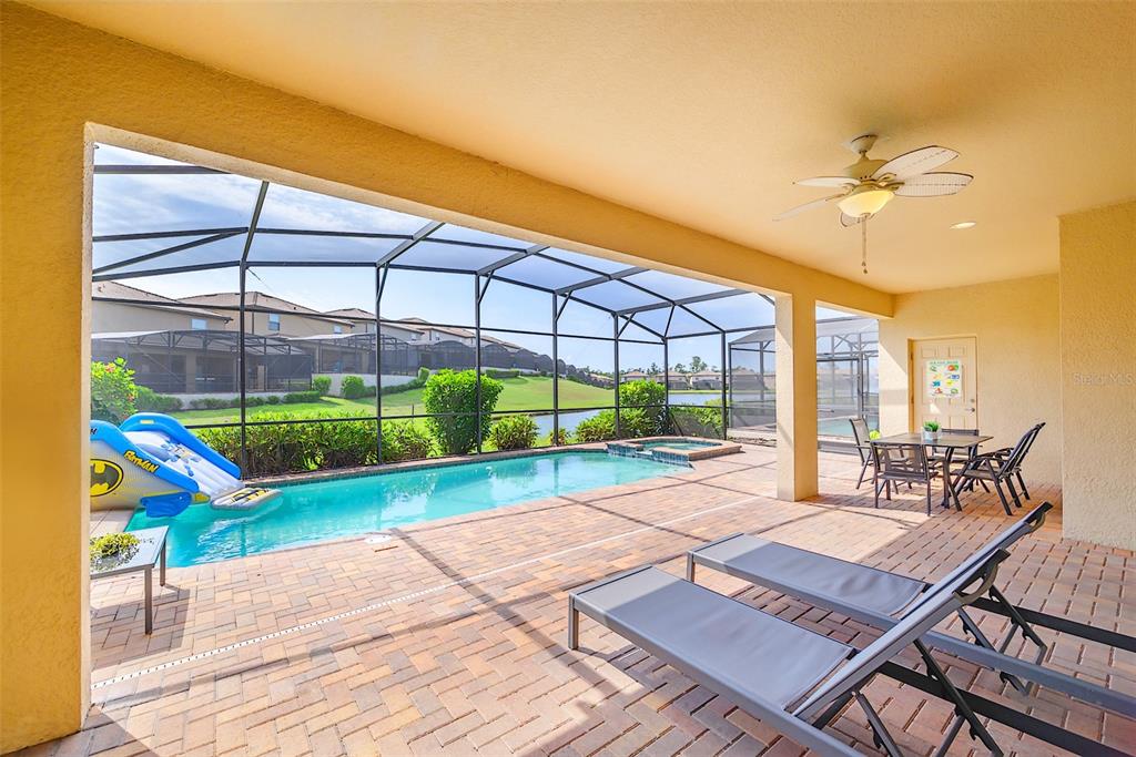 A covered patio features a screened-in pool, a water slide, and outdoor dining furniture — 1893 GOBI DRIVE, KISSIMMEE, FL