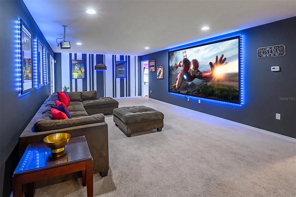 A home theater room features a large projection screen, sectional sofa, and blue LED lighting — 1893 GOBI DRIVE, KISSIMMEE, FL