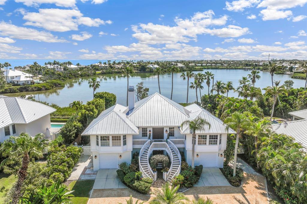 An elevated coastal house with a curved staircase, metal roof, and views of a lake — 1678 JOSE GASPAR DRIVE, BOCA GRANDE, FL