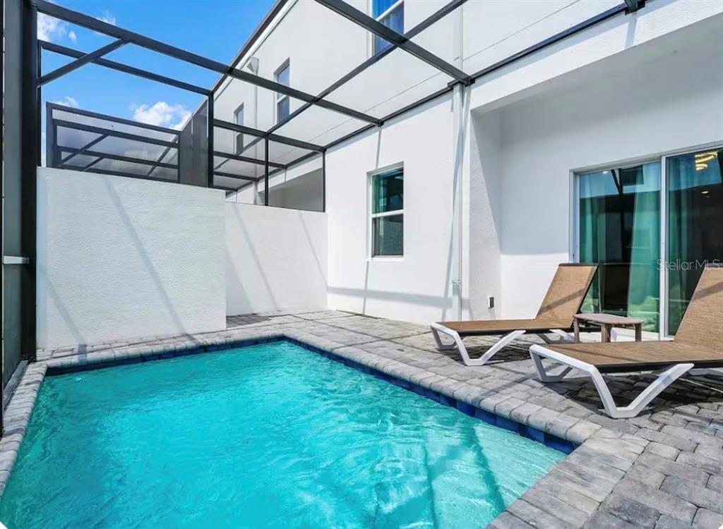 A small swimming pool sits on a paved patio enclosed by a screened-in lanai — 363 FAMAGUSTA DRIVE, DAVENPORT, FL