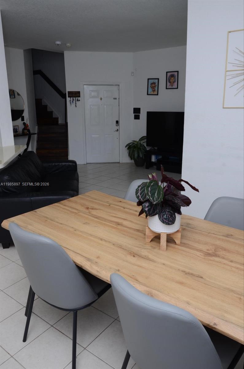 A dining area with a wooden table and gray chairs overlooks a living room — 12505 SW 124th Ct, Miami FL 33186, MIAMI, FL