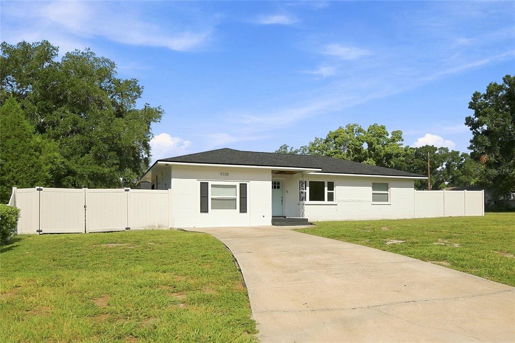 A single-story white house with a concrete driveway and a white vinyl privacy fence — 9708 FOREST HILLS DRIVE, TAMPA, FL