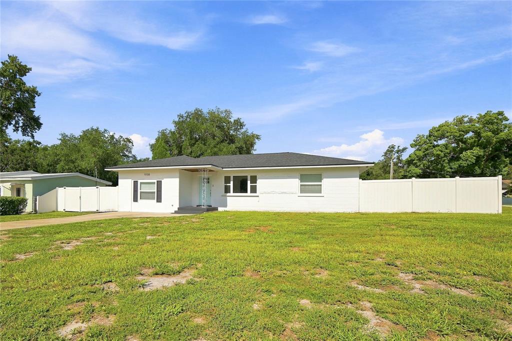 A single-story white house with a dark roof and a large front lawn — 9708 FOREST HILLS DRIVE, TAMPA, FL