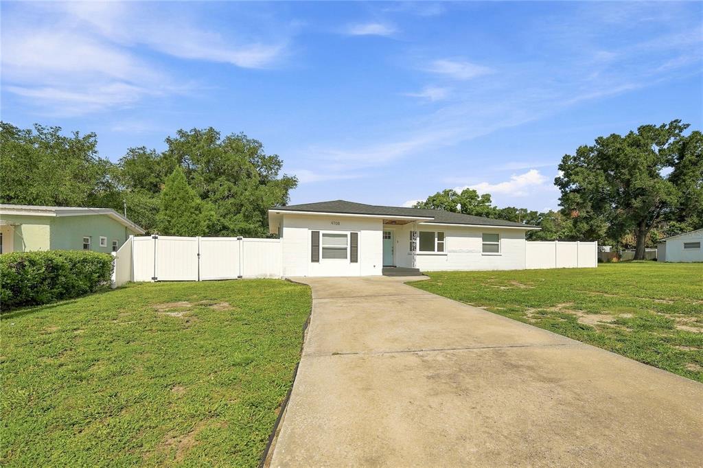 A white single-story house with a concrete driveway and a white vinyl privacy fence — 9708 FOREST HILLS DRIVE, TAMPA, FL