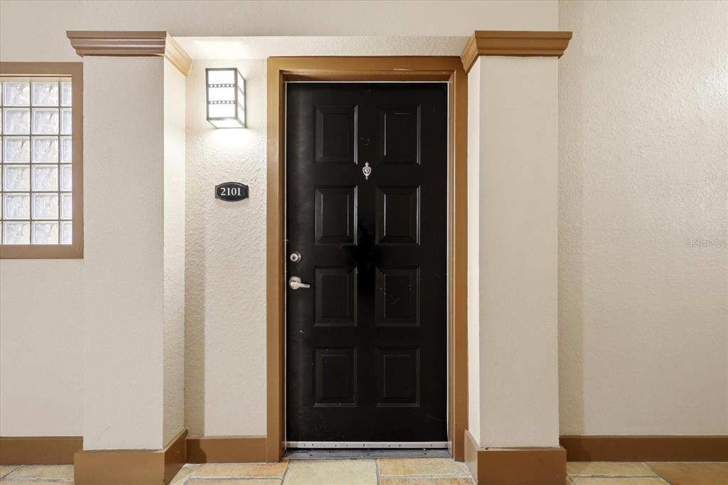 A black front door with a house number sign sits between two beige pillars — 4221 W SPRUCE STREET UNIT 2101, TAMPA, FL