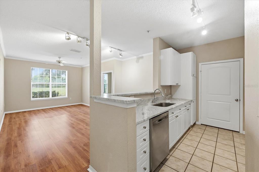 A kitchen with white cabinets and marble countertops overlooks a living area with wood flooring — 4221 W SPRUCE STREET UNIT 2101, TAMPA, FL