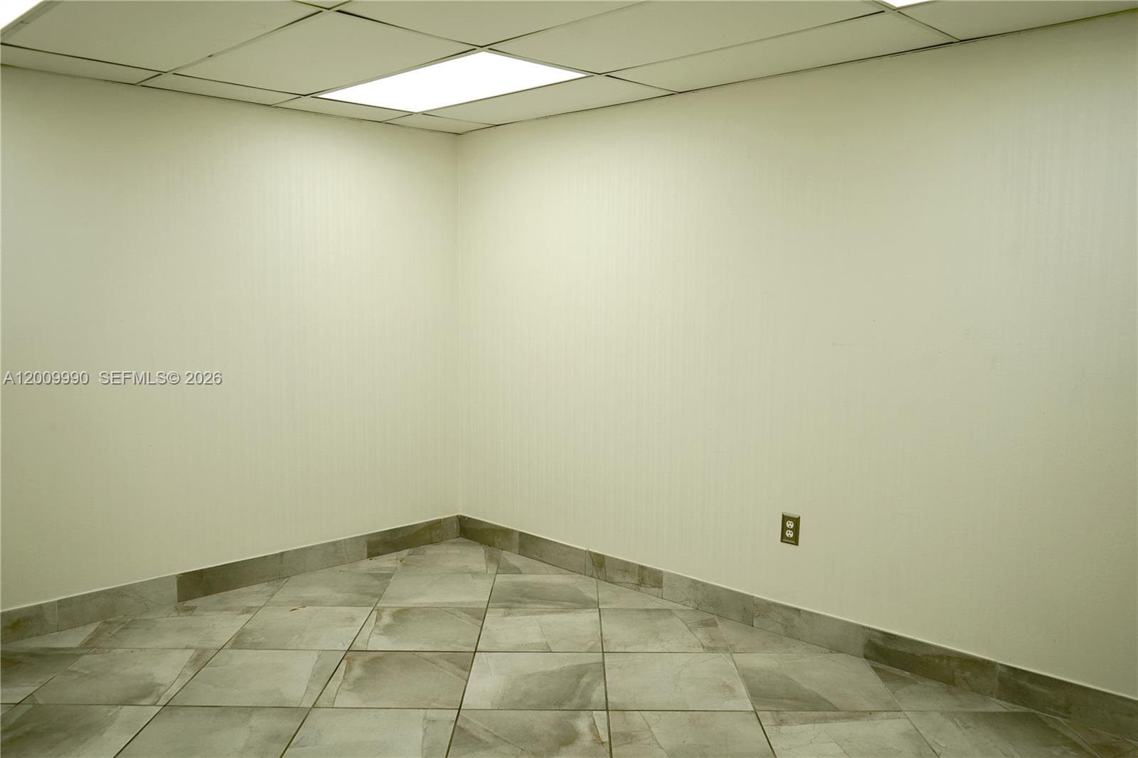 An empty room features beige walls, a drop ceiling with a light, and tiled flooring — 150 Westward Dr # 4, Miami Springs FL 33166, MIAMI SPRINGS, FL