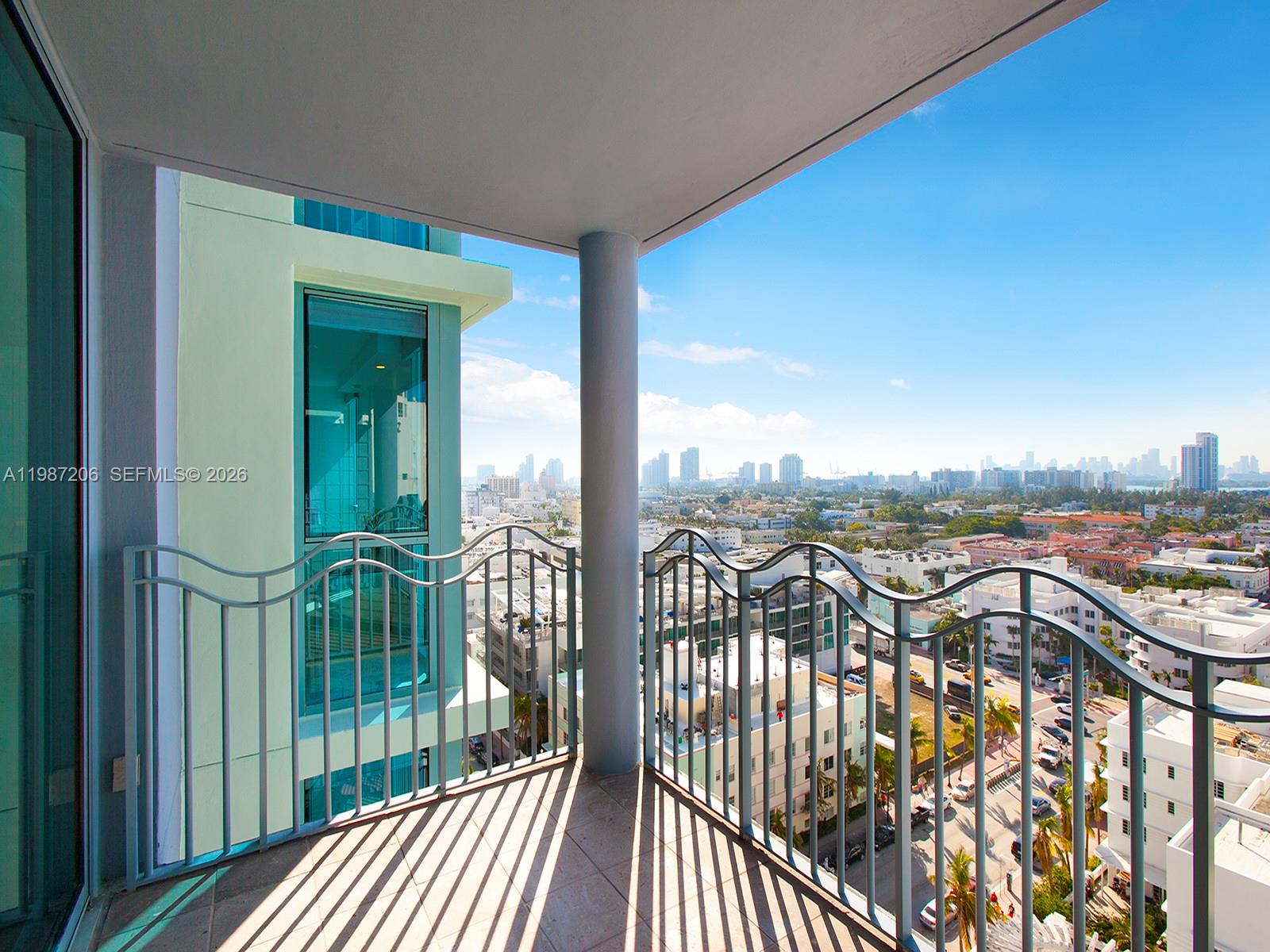 A high-rise balcony with a metal railing overlooks a city skyline under a blue sky — 1500 Ocean Dr # 10, Miami Beach FL 33139, MIAMI BEACH, FL
