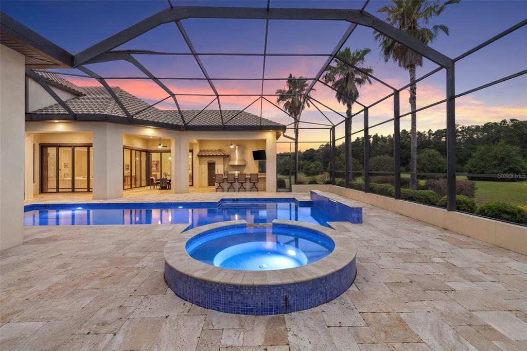 A screened-in pool and spa area with a covered patio and outdoor kitchen — 17301 BALLMONT PARK DRIVE, ODESSA, FL