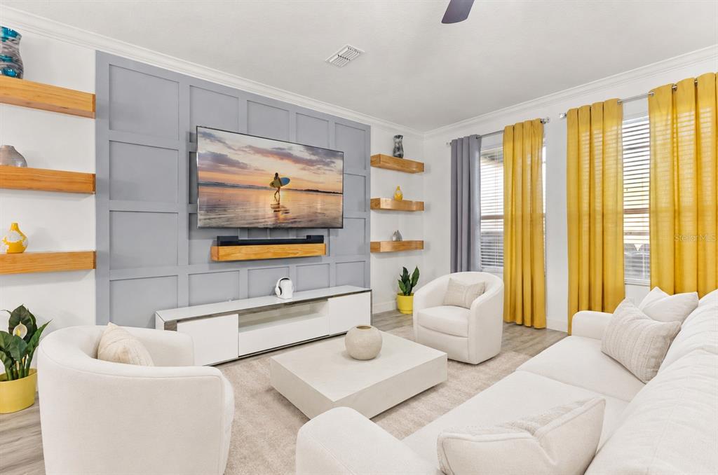 A living room features a grey paneled accent wall, floating wood shelves, and yellow curtains — 1452 SOURWOOD DRIVE, OCOEE, FL