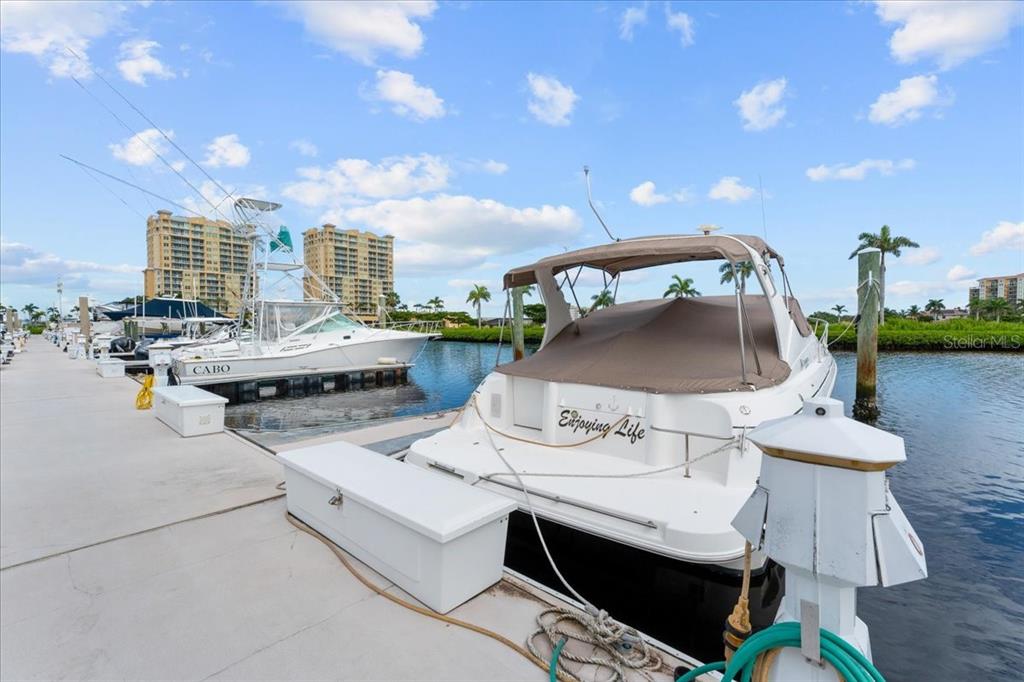 Two boats are docked at a concrete pier under a blue sky with clouds — 102 RIVIERA DUNES WAY UNIT N-29, PALMETTO, FL