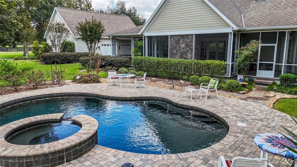 A backyard features a swimming pool with an attached spa and a stone-paved patio area — 1198 SW 104TH STREET ROAD, OCALA, FL