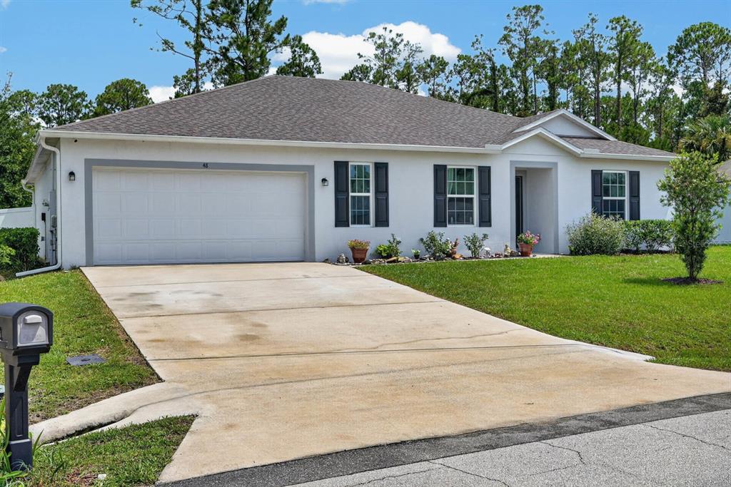 A single-story house with a white stucco exterior, a two-car garage, and a concrete driveway — 48 PORCUPINE DRIVE, PALM COAST, FL