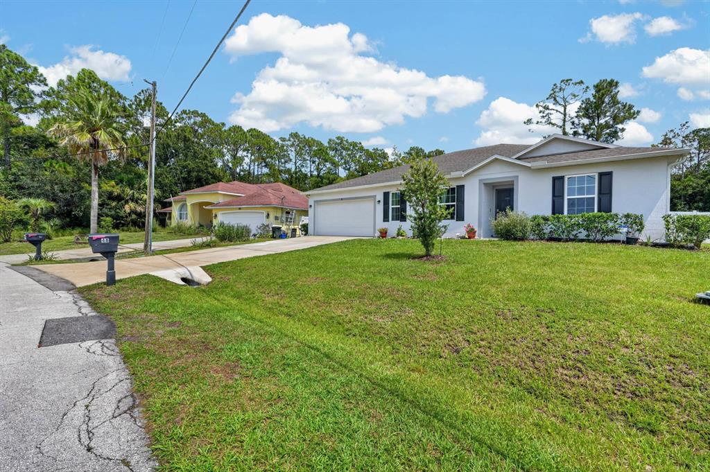 A white single-story house with a two-car garage and a front lawn — 48 PORCUPINE DRIVE, PALM COAST, FL