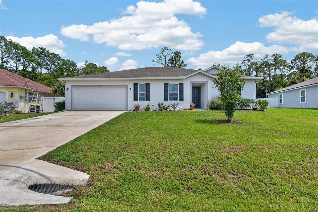 A single-story house with a white exterior, a two-car garage, and a front lawn — 48 PORCUPINE DRIVE, PALM COAST, FL