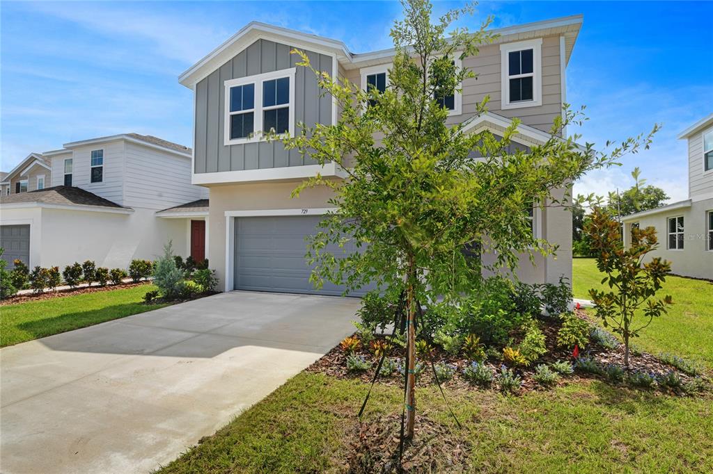 A two-story suburban house with a gray garage, light siding, and a front yard tree — 729 LAKE DELL AVENUE, DUNDEE, FL