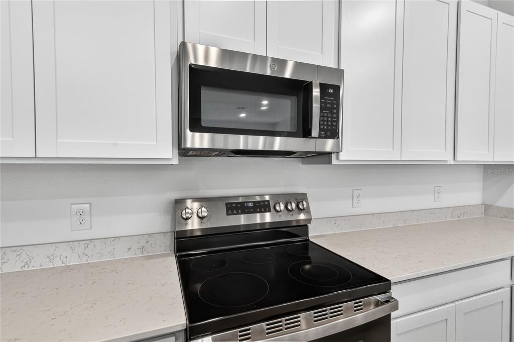 A kitchen features white cabinets, a stainless steel microwave, and a black electric range — 729 LAKE DELL AVENUE, DUNDEE, FL