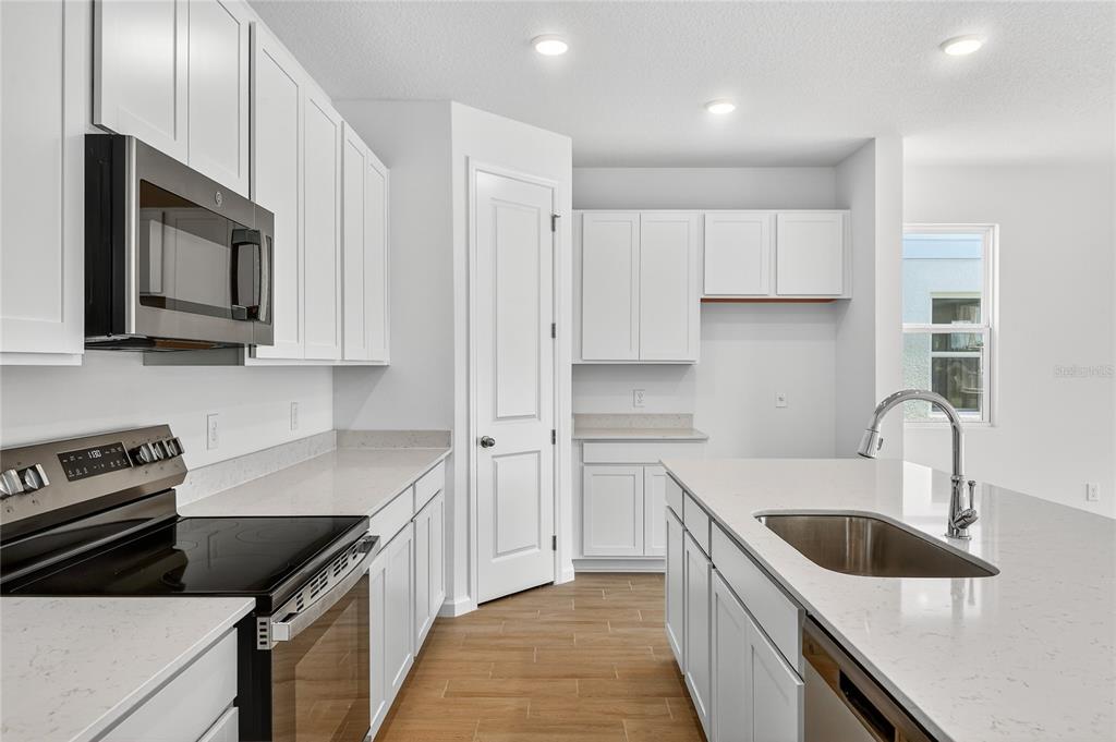 A modern kitchen features white cabinets, quartz countertops, stainless steel appliances, and a center island — 729 LAKE DELL AVENUE, DUNDEE, FL