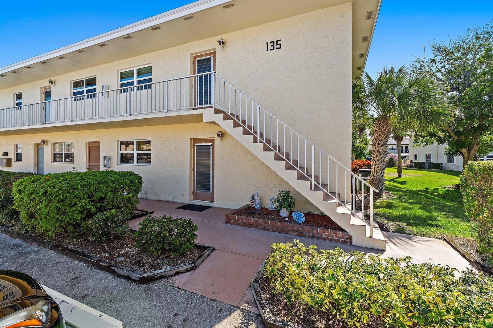 A two-story apartment building exterior features a white staircase leading to an upper-level balcony — 2950 SE Ocean Blvd. # 8, Stuart FL 34996, STUART, FL