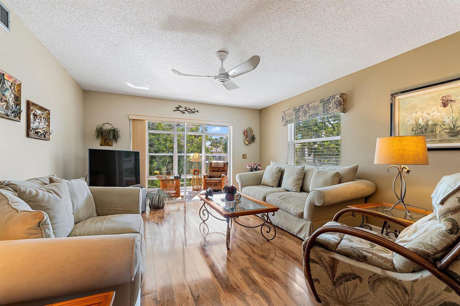 A living room features light-colored sofas, a glass-top coffee table, and wood-look flooring — 2950 SE Ocean Blvd. # 8, Stuart FL 34996, STUART, FL